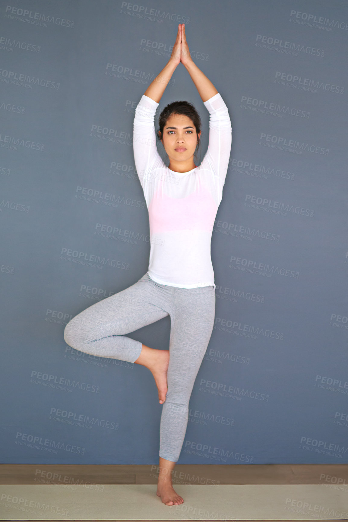 Buy stock photo Full length shot of a sporty young woman doing yoga against a grey background