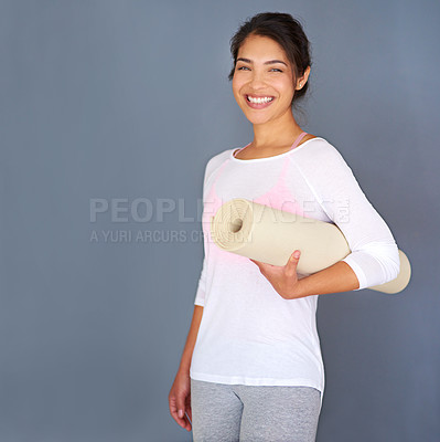 Buy stock photo Cropped shot of a sporty young woman holding her yoga mat against a grey background
