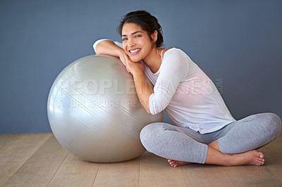 Buy stock photo Full length shot of a sporty young woman leaning on a pilates ball against a grey background