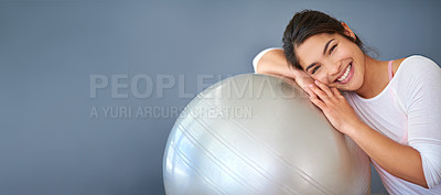 Buy stock photo Cropped shot of a sporty young woman leaning on a pilates ball against a grey background