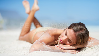 Buy stock photo Shot of an attractive young woman lying on the beach in a bikini