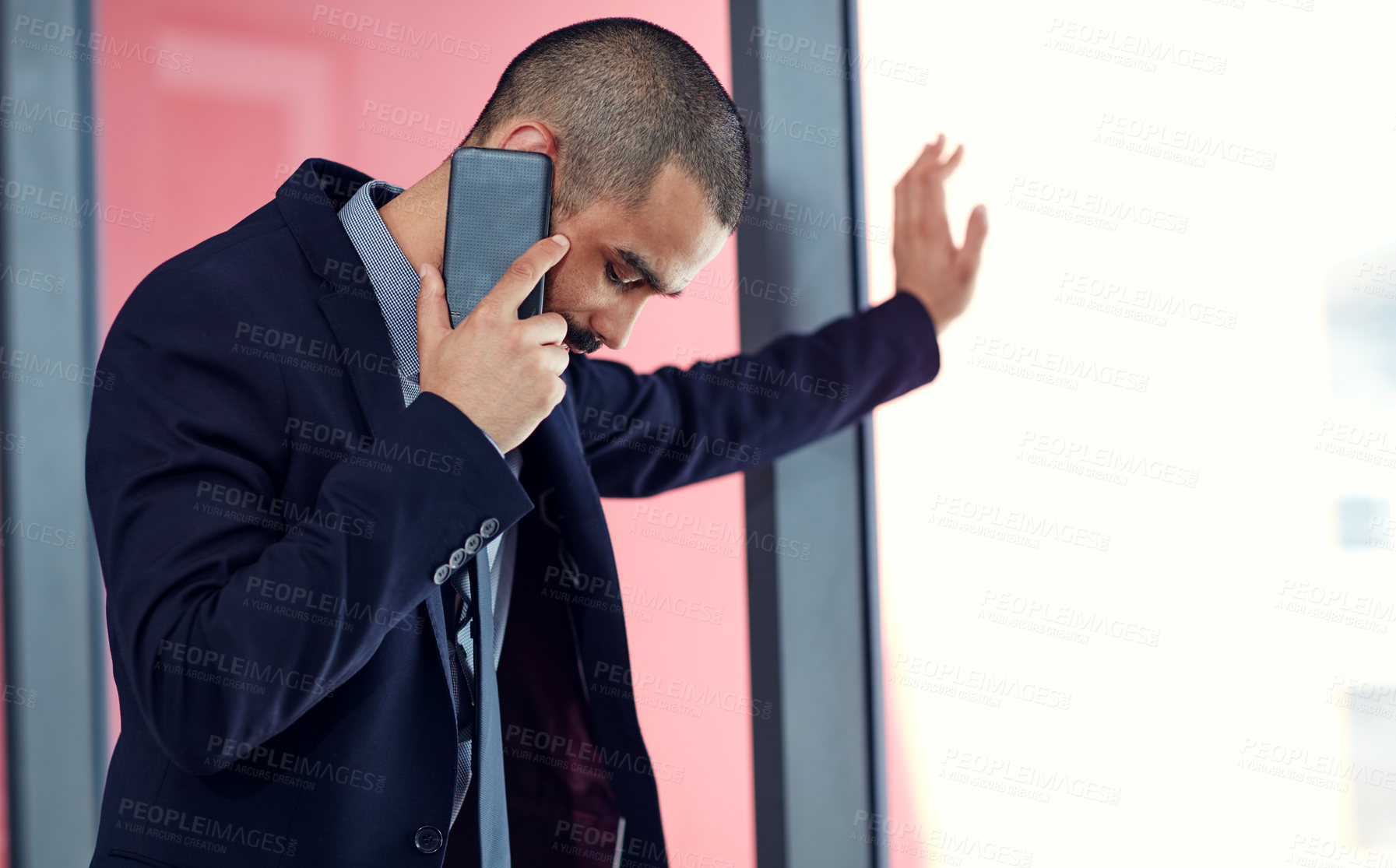 Buy stock photo Shot of a young businessman talking on a cellphone in his office