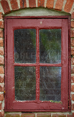 Buy stock photo Old dirty window of a brick wall house or home. Ancient casement with red metal frame on a historic building with a clumpy paint texture. Exterior details of a windowsill in a traditional country town