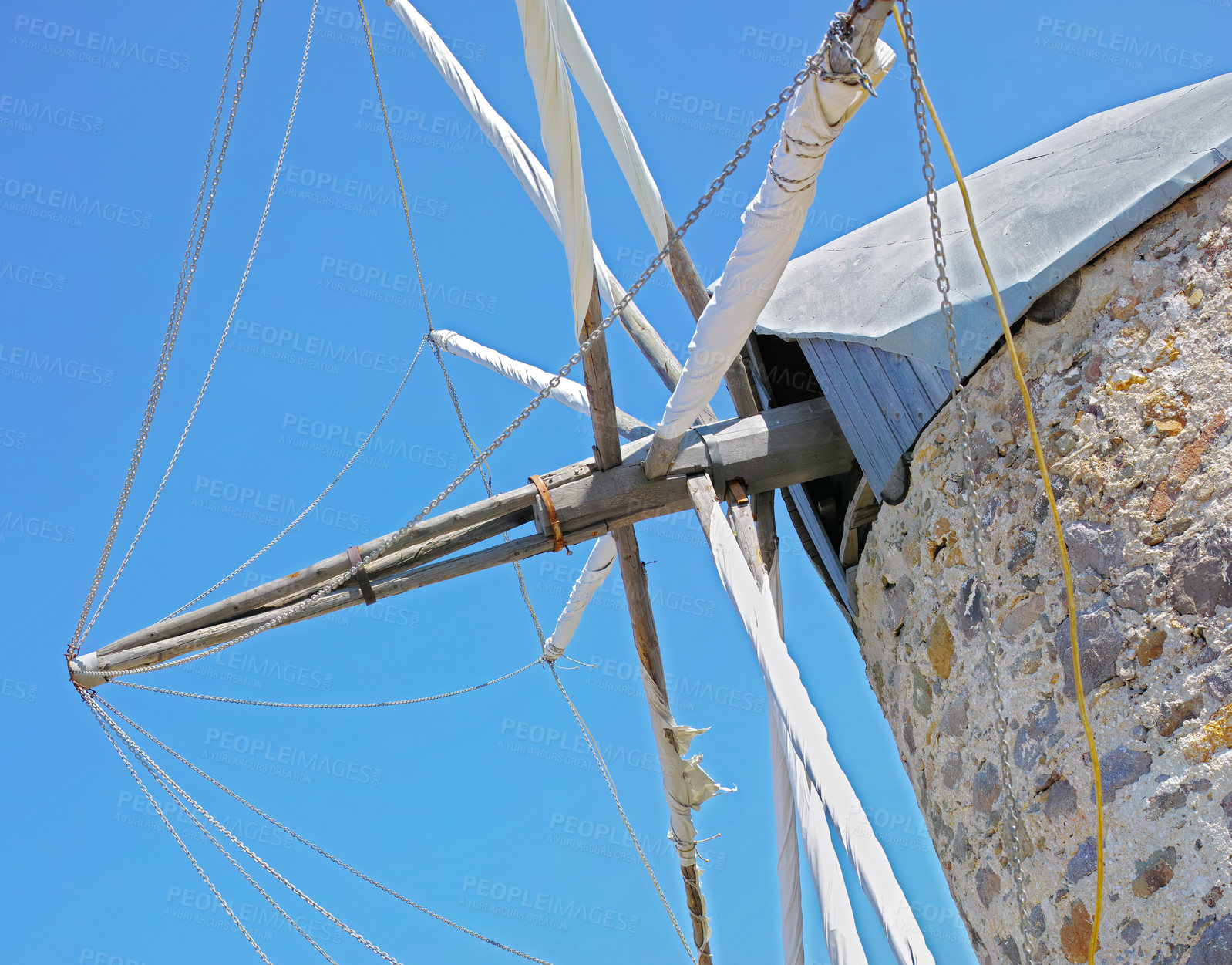 Buy stock photo Closeup of an old white windmill on a brick building against a blue sky. Below of an historic or antique wind turbine house in traditional sustainable village with exterior architectural detail