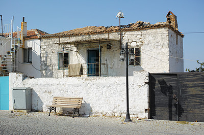 Buy stock photo An old white farmhouse exterior. Ancient rustic house on the street with a broken damaged roof, tiny square windows and brick walls. Open windows in thick stone wall of an weathered antique building