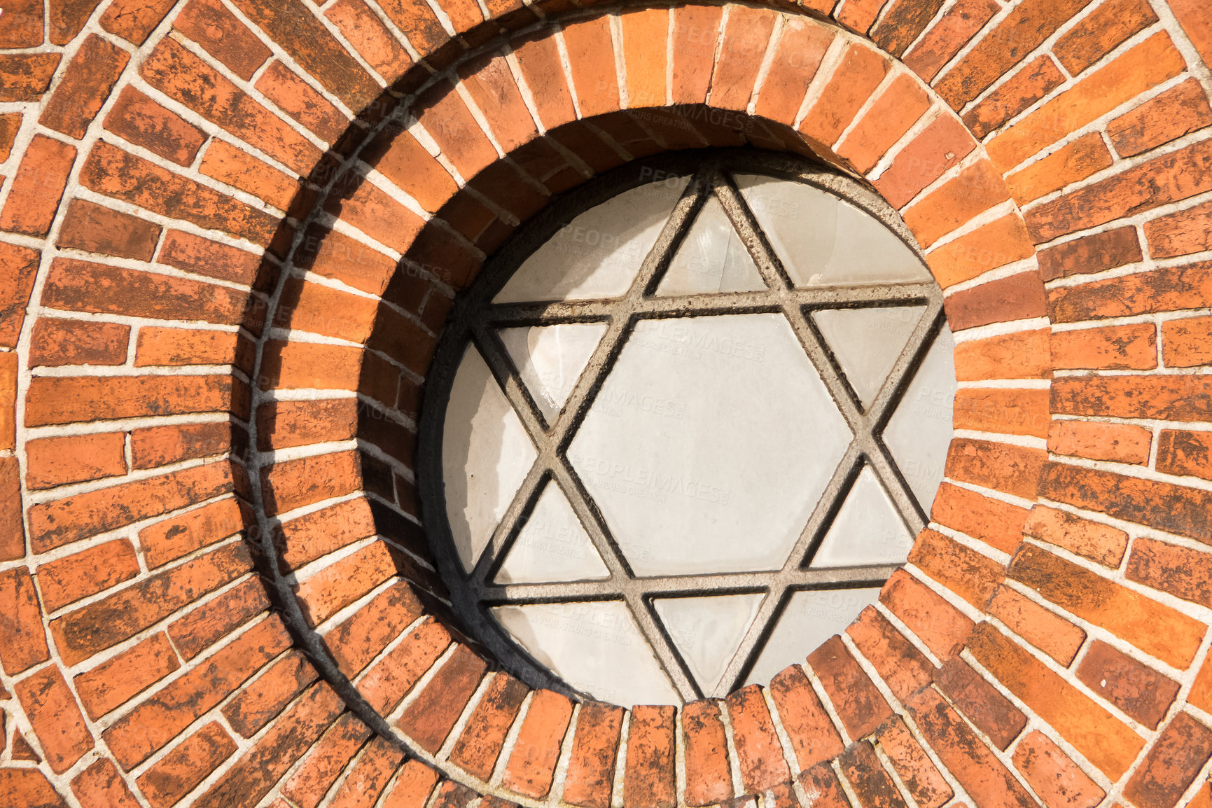 Buy stock photo View of a pentagram sign and symbol on an old round window on a red brick wall. Vintage glass with metal frame and pentagon on historic church building and background. Architecture circular design