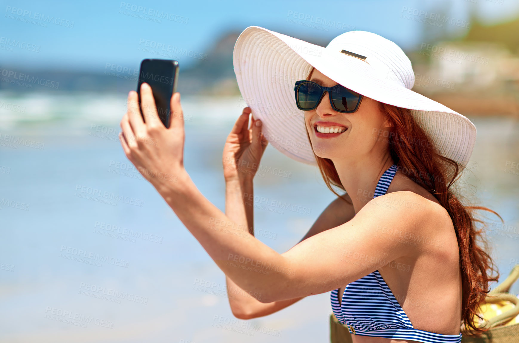 Buy stock photo Shot of a beautiful young woman taking a selfie at the beach