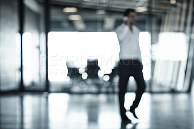 Buy stock photo Full length shot of a businessman using his cellphone while walking through an office