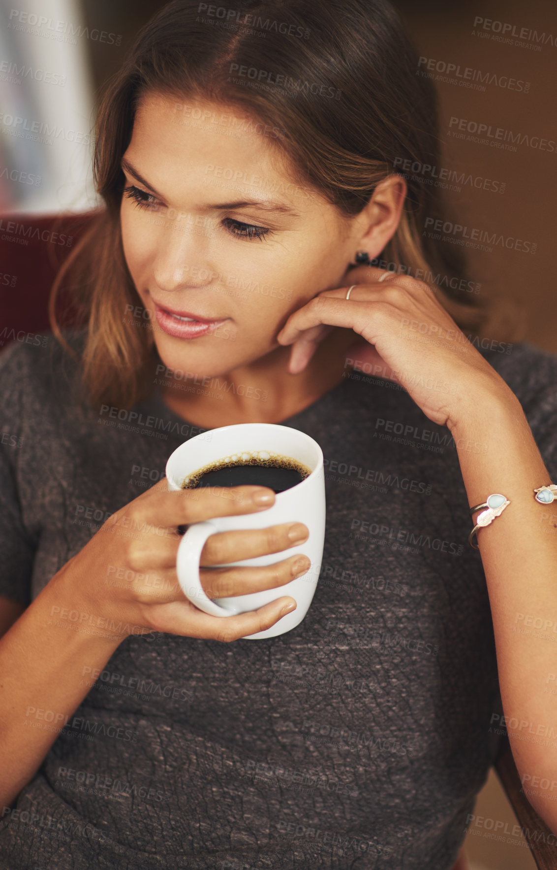 Buy stock photo Shot of a young woman enjoying a cup of coffee at home