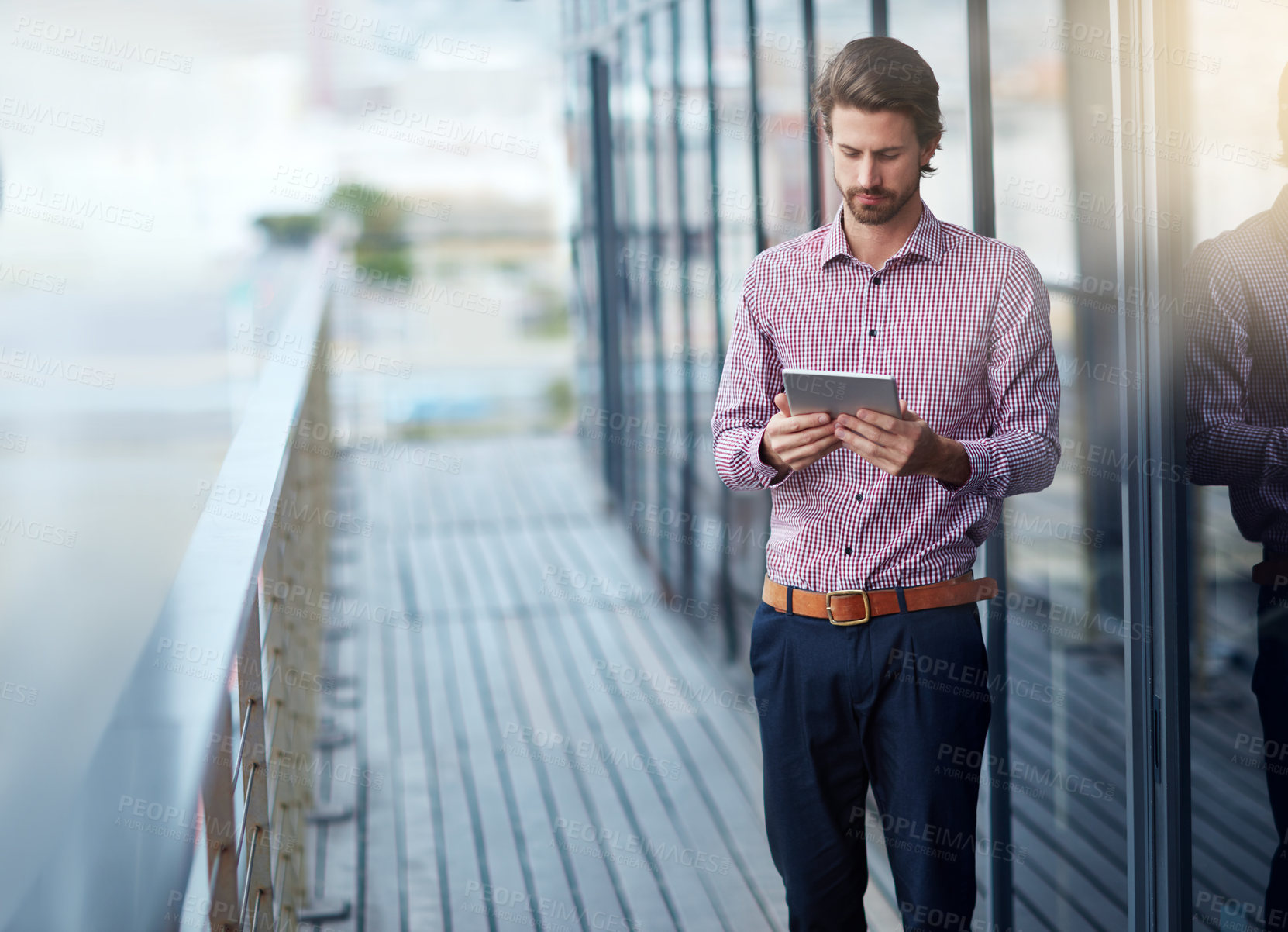 Buy stock photo Shot of a young businessman using a digital tablet outside of an office building