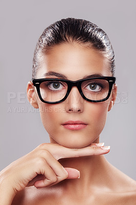 Buy stock photo Studio portrait of a beautiful young woman wearing glasses against a gray background