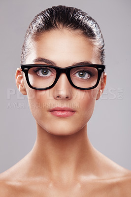 Buy stock photo Studio portrait of a beautiful young woman wearing glasses against a gray background