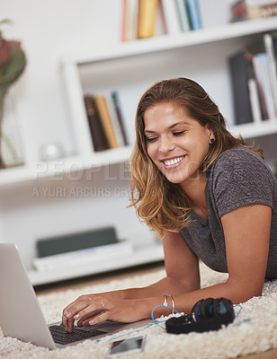 Buy stock photo Shot of a young woman relaxing at home with her laptop
