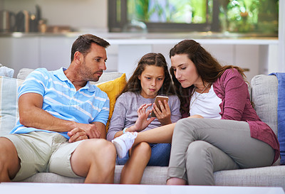 Buy stock photo Cropped shot of a young girl showing her parents something on her cellphone