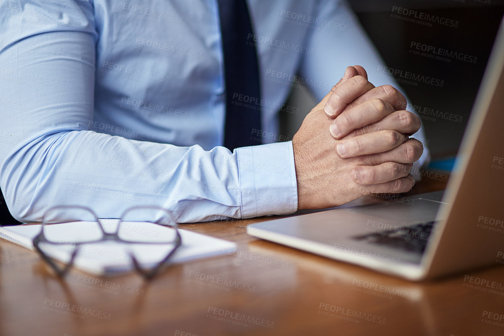 Buy stock photo Cropped shot of a businessman clasping his hands nervously while working in his office