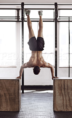 Buy stock photo Rearview shot of a young man working out in the gym