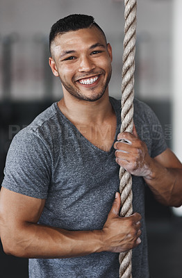 Buy stock photo Cropped portrait of a young man climbing a rope at the gym