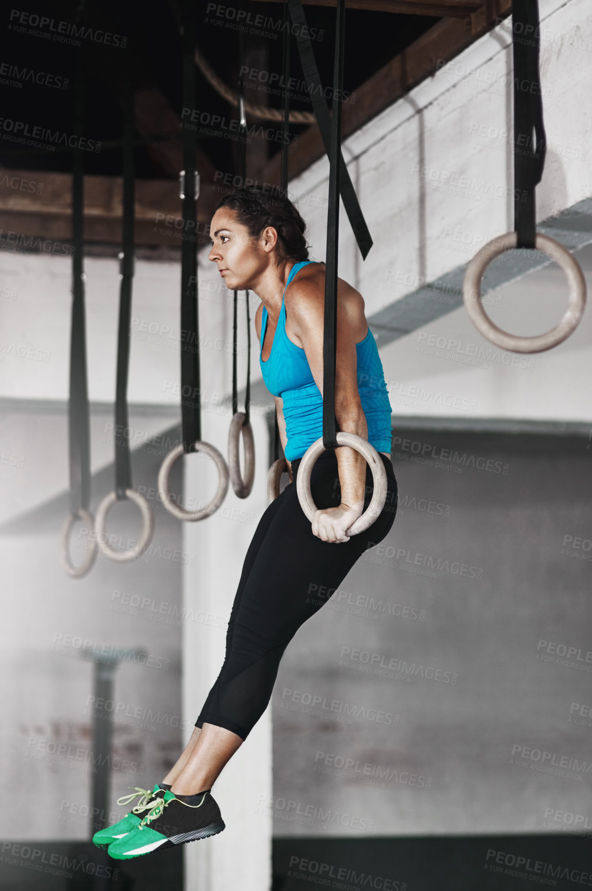 Buy stock photo Full length shot of a young woman working out on the gymnastics rings