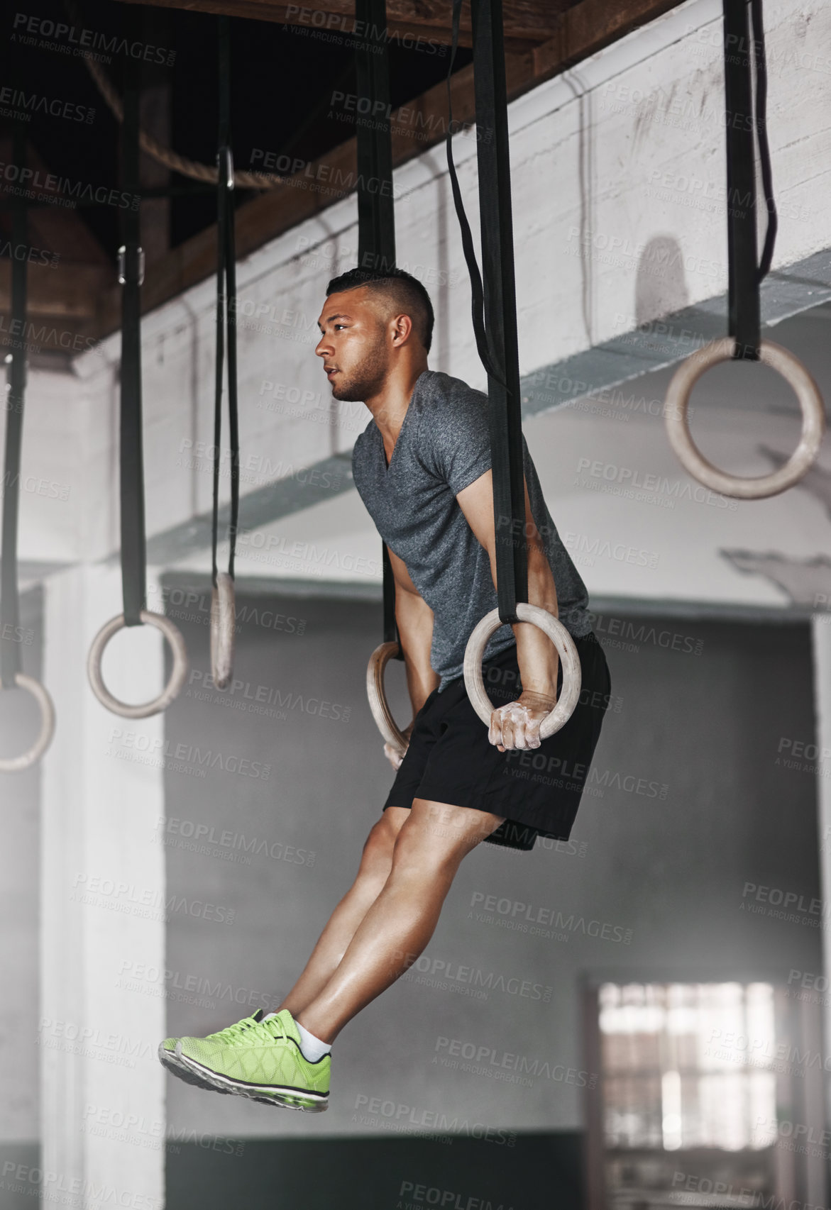 Buy stock photo Full length shot of a young man working out on the gymnastics rings