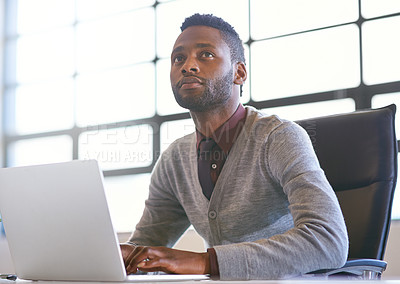 Buy stock photo Shot of a thoughtful young businessman using a laptop in an office