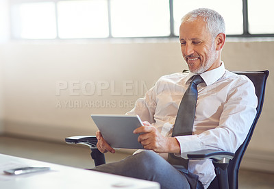 Buy stock photo Shot of a mature businessman using a digital tablet in an office