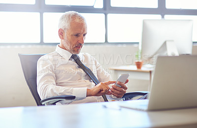 Buy stock photo Shot of a mature businessman using his phone in the office