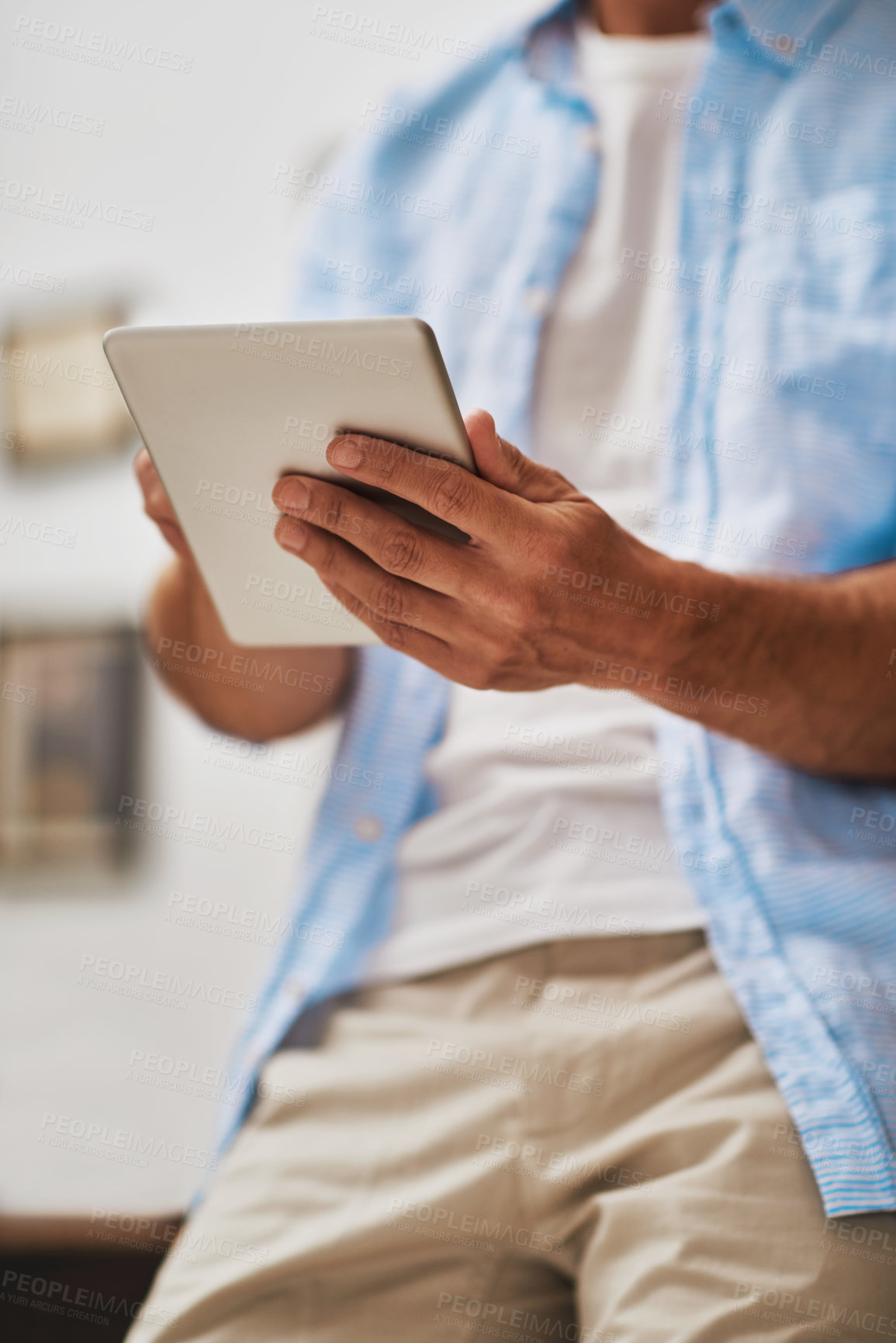 Buy stock photo Cropped shot of a businessman using his digital tablet at home