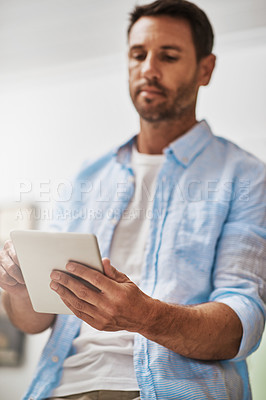Buy stock photo Cropped shot of a businessman using his digital tablet at home