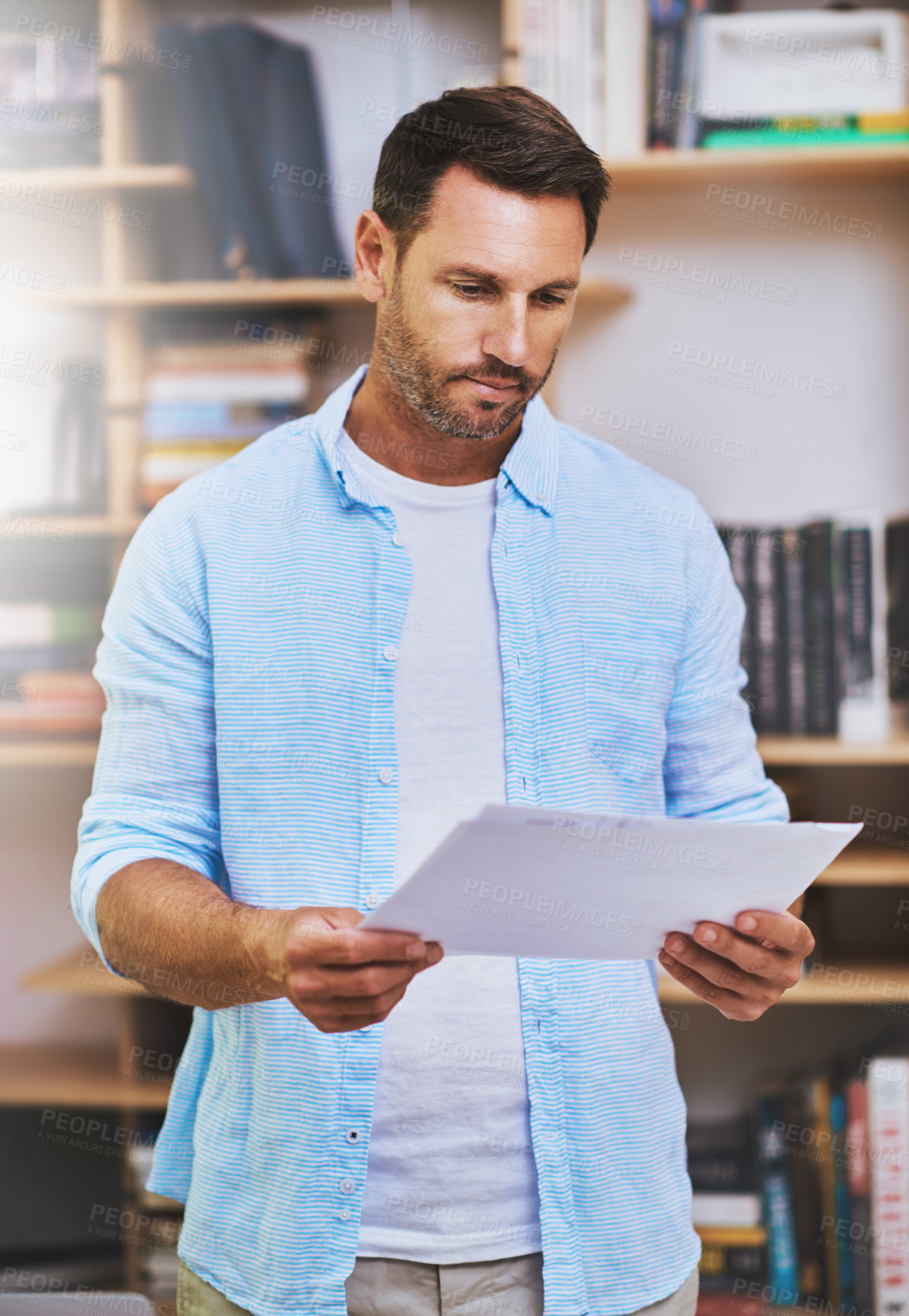 Buy stock photo Cropped shot of a businessman reading some paperwork at home