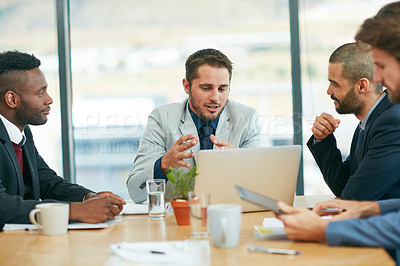 Buy stock photo Shot of a team of colleagues having a meeting around a laptop in a modern office