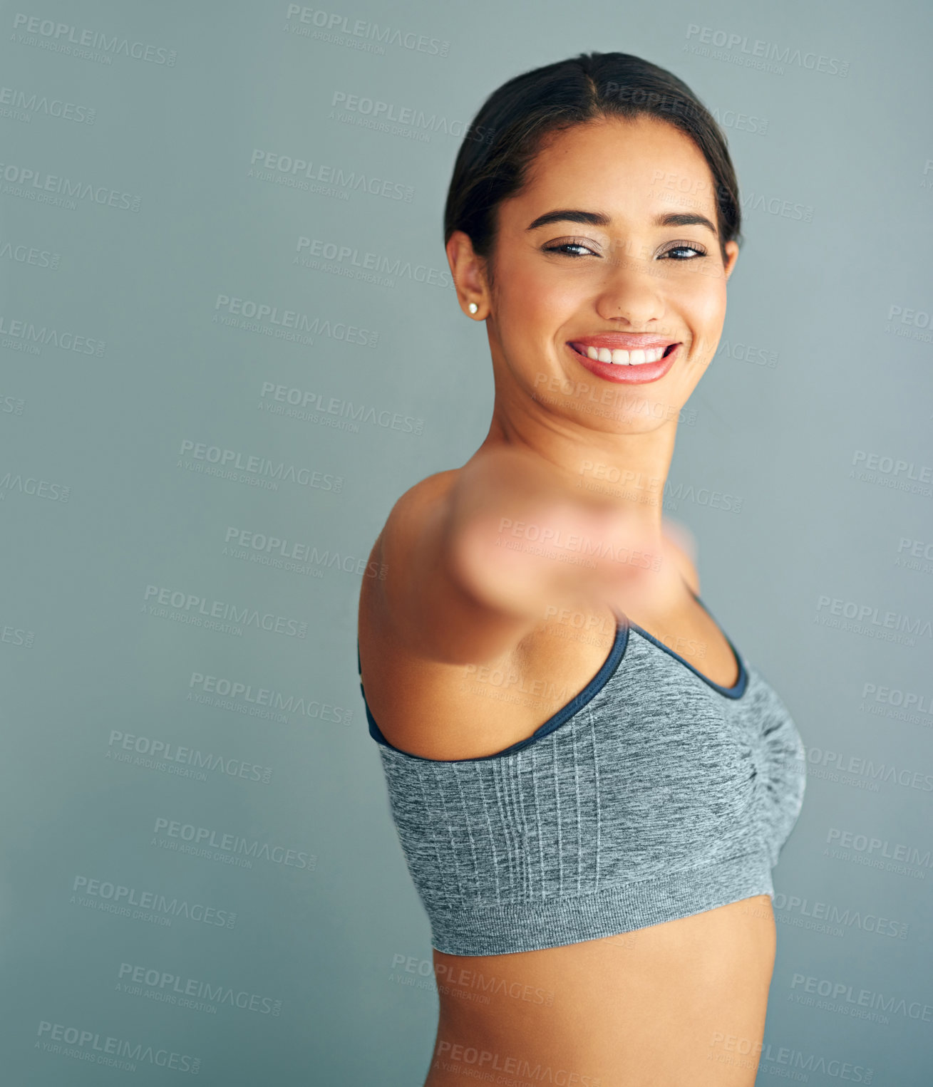 Buy stock photo Cropped shot of a young woman stretching against a grey background