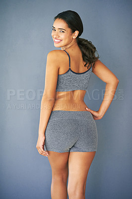Buy stock photo Rearview shot of a sporty young woman posing against a grey background