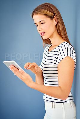 Buy stock photo Shot of a young woman using a digital tablet against a blue background