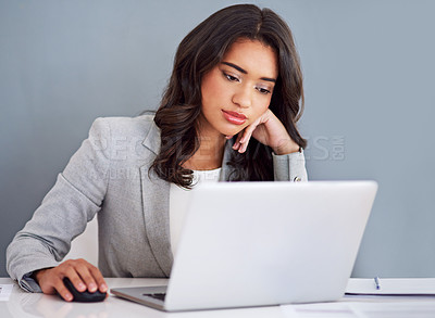 Buy stock photo Cropped shot of a young businesswoman looking bored while working on her laptop