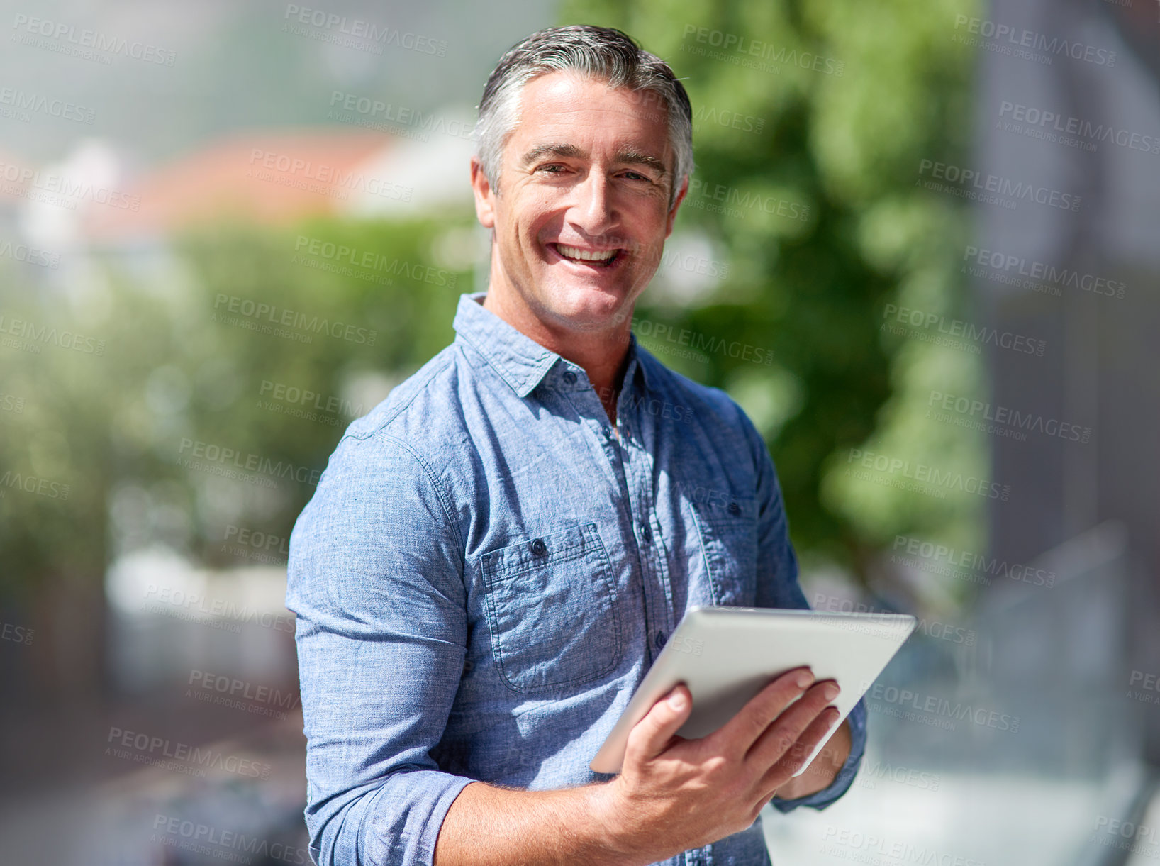 Buy stock photo Portrait of a casually dressed businessman using a digital tablet outside