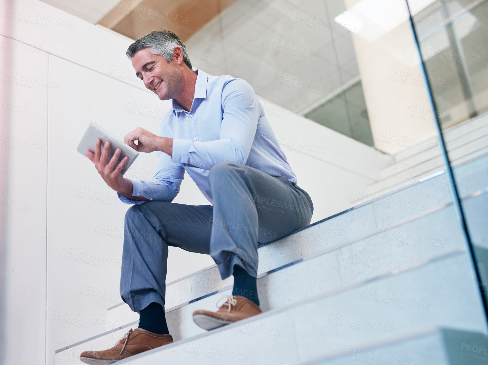 Buy stock photo Shot of a mature businessman using a digital tablet on the stairs in a modern office