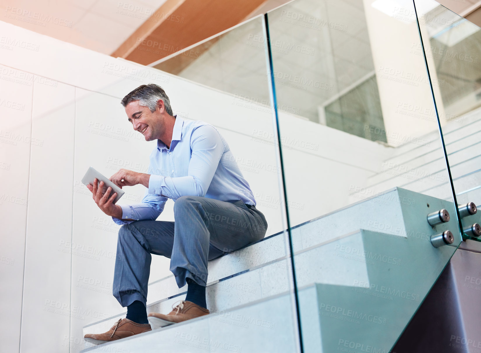 Buy stock photo Shot of a mature businessman using a digital tablet on the stairs in a modern office