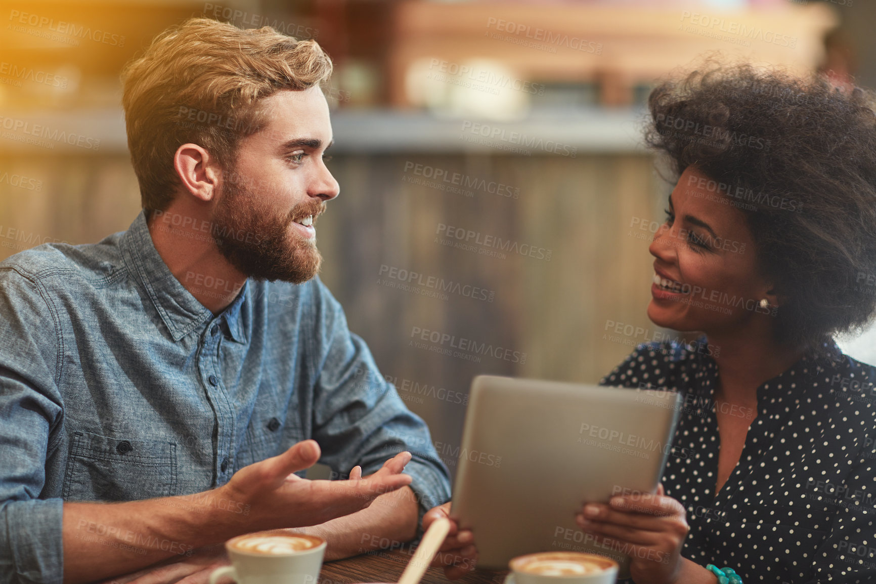 Buy stock photo Couple, tablet and happy with discussion in cafe for social media post, bonding and online shopping. Interracial, people and smile in coffee shop with tech app for web browsing, conversation or relax
