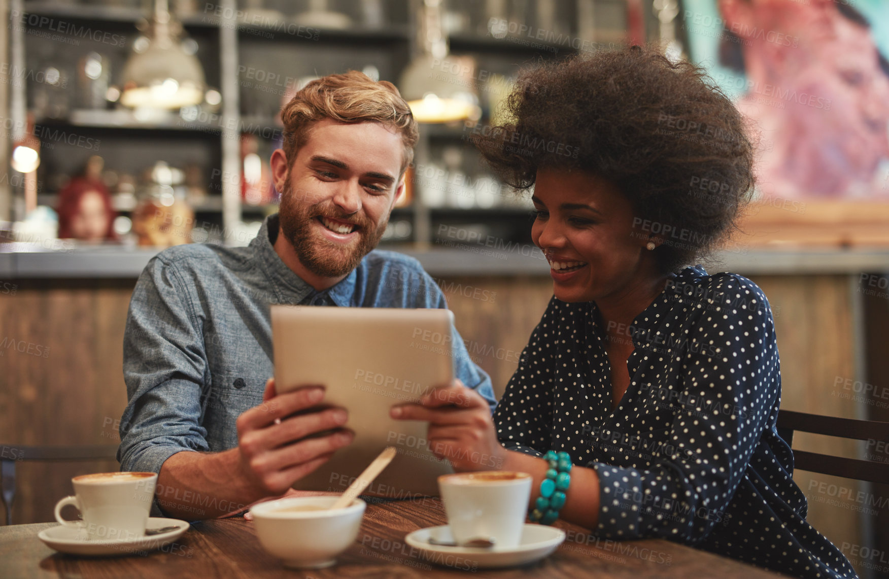 Buy stock photo Couple, tablet and happy on date in coffee shop with social media streaming, bonding and online information. Interracial, people and smile in cafe with tech app for post update, discussion and relax