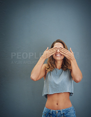 Buy stock photo Studio shot of a young woman covering her eyes against a gray background