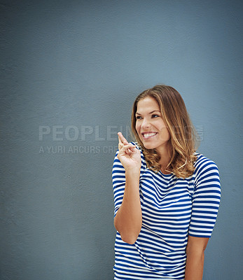 Buy stock photo Studio shot of a young woman crossing her fingers against a gray background