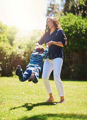 Buy stock photo Shot of a mother playfully swinging her son around at the park