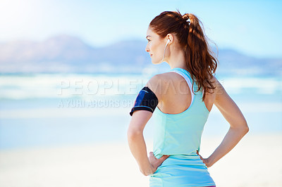 Buy stock photo Cropped shot of a young woman standing with her hands on her hips on the beach