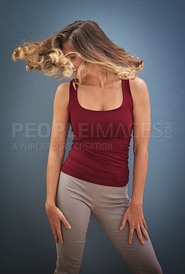 Buy stock photo Shot of a young woman twirling her hair against a gray background