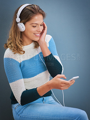 Buy stock photo Studio shot of a young woman listening to music against a gray background