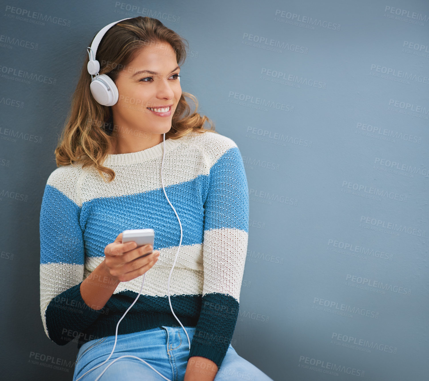 Buy stock photo Woman, phone and headphones in studio for listening, texting and mock up space by background. Person, smartphone and audio streaming with subscription, music and sound with mobile app for chat