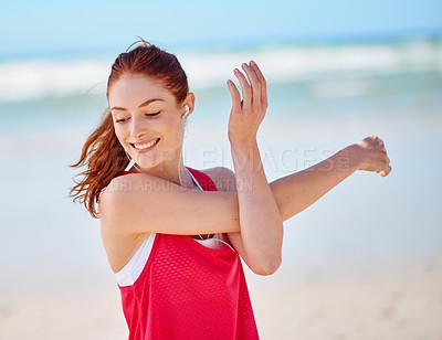 Buy stock photo Cropped shot of a young woman stretching before her run on the beach