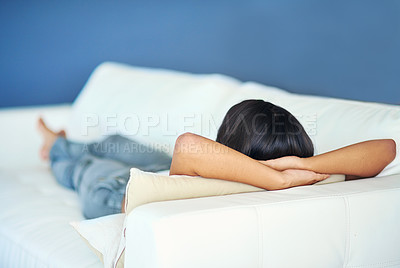 Buy stock photo Rearview shot of a young woman lying on the sofa at home