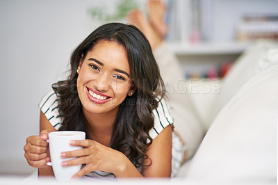 Buy stock photo Cropped portrait of a young woman drinking coffee while relaxing on her sofa at home