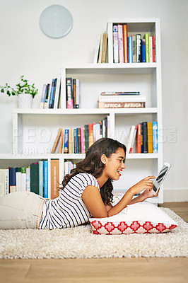 Buy stock photo Cropped shot of a young woman using her tablet while relaxing at home